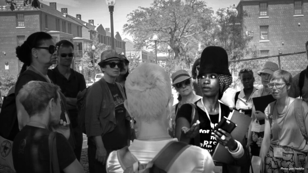 Photograph of Shana m griffin speaking to a group of people outside in New Orleans.